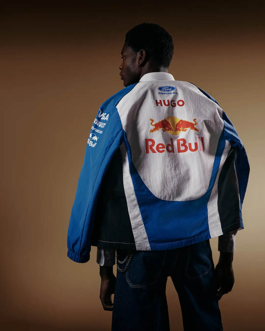 Rear view of a model wearing the Visa Cash App Racing Bulls blue and white team jacket during the VCARB 2026 Team Kit Launch, with Red Bull branding visible on the back.