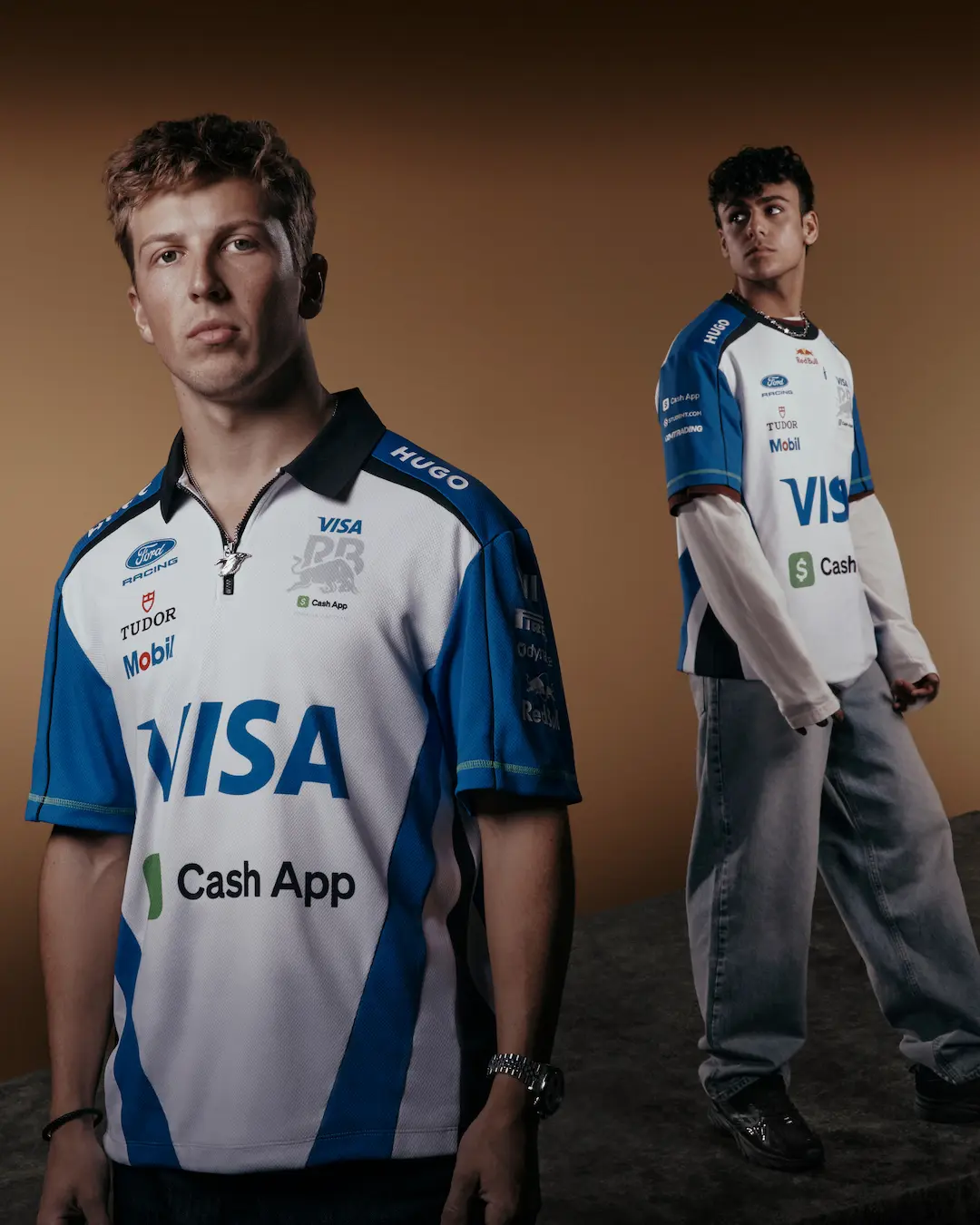 Two Visa Cash App Racing Bulls drivers wearing the white and blue team shirt during the VCARB 2026 Team Kit Launch, photographed on a studio set.